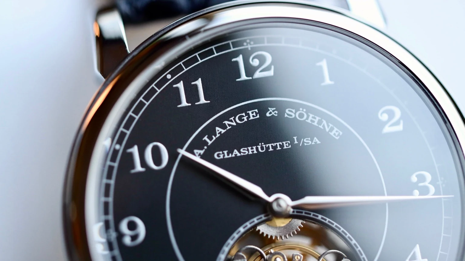 Close-up of a black watch dial with silver hands and applied numerals