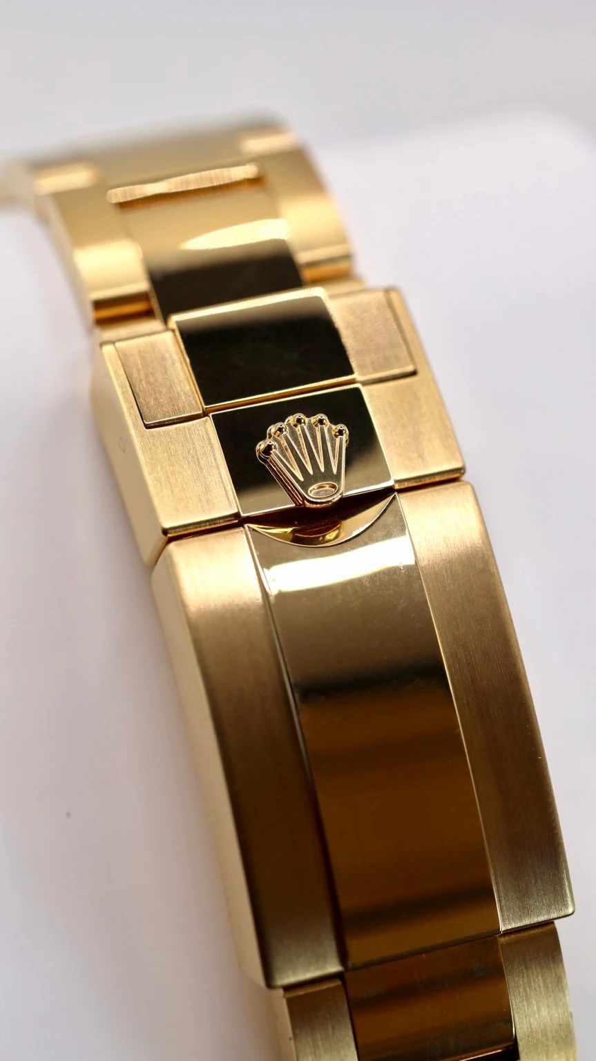 Close-up of the brushed and polished surfaces of a yellow-gold-finished bracelet clasp
